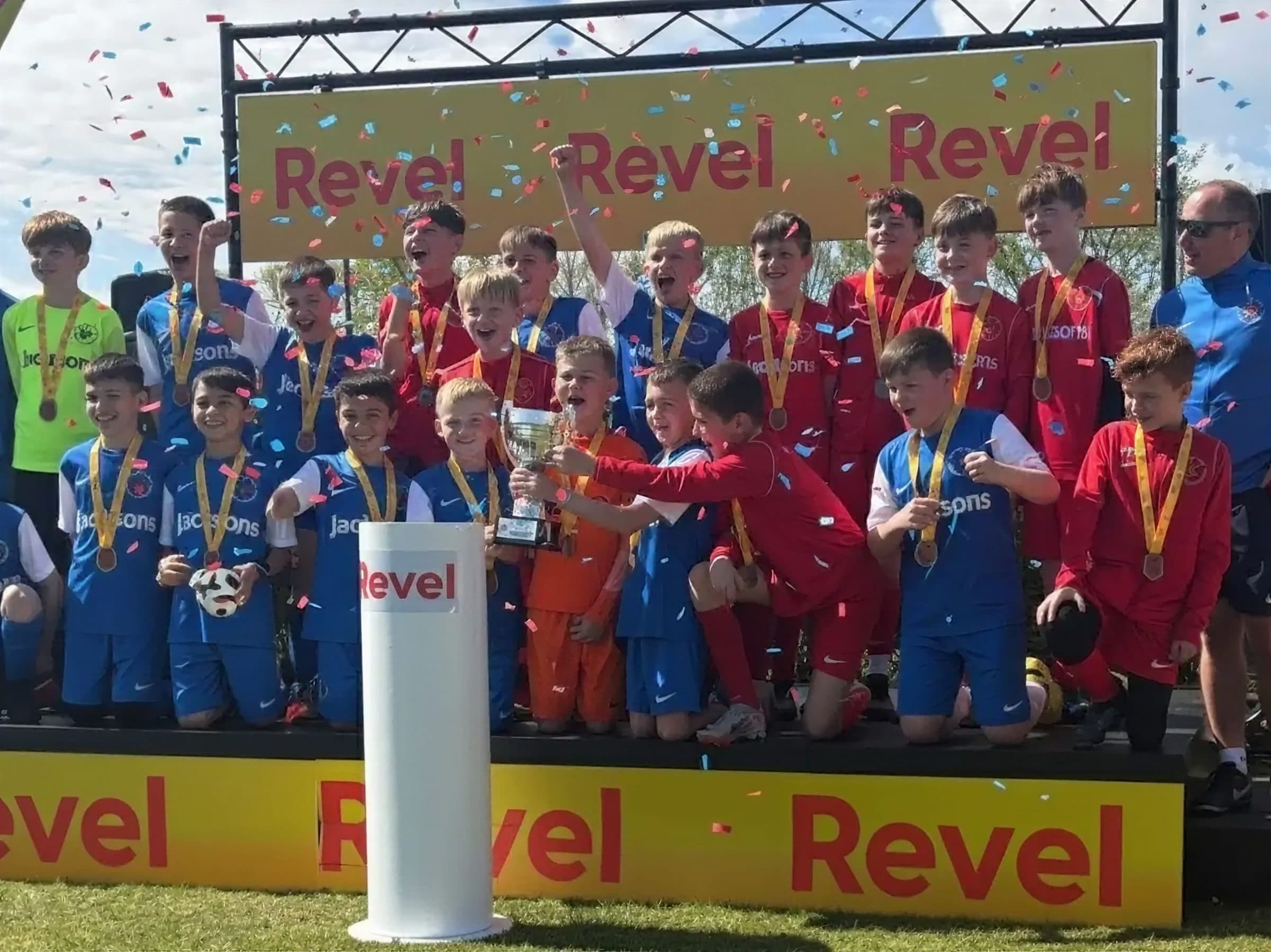 A squad lifting the cup on the Revel podium under falling confetti
