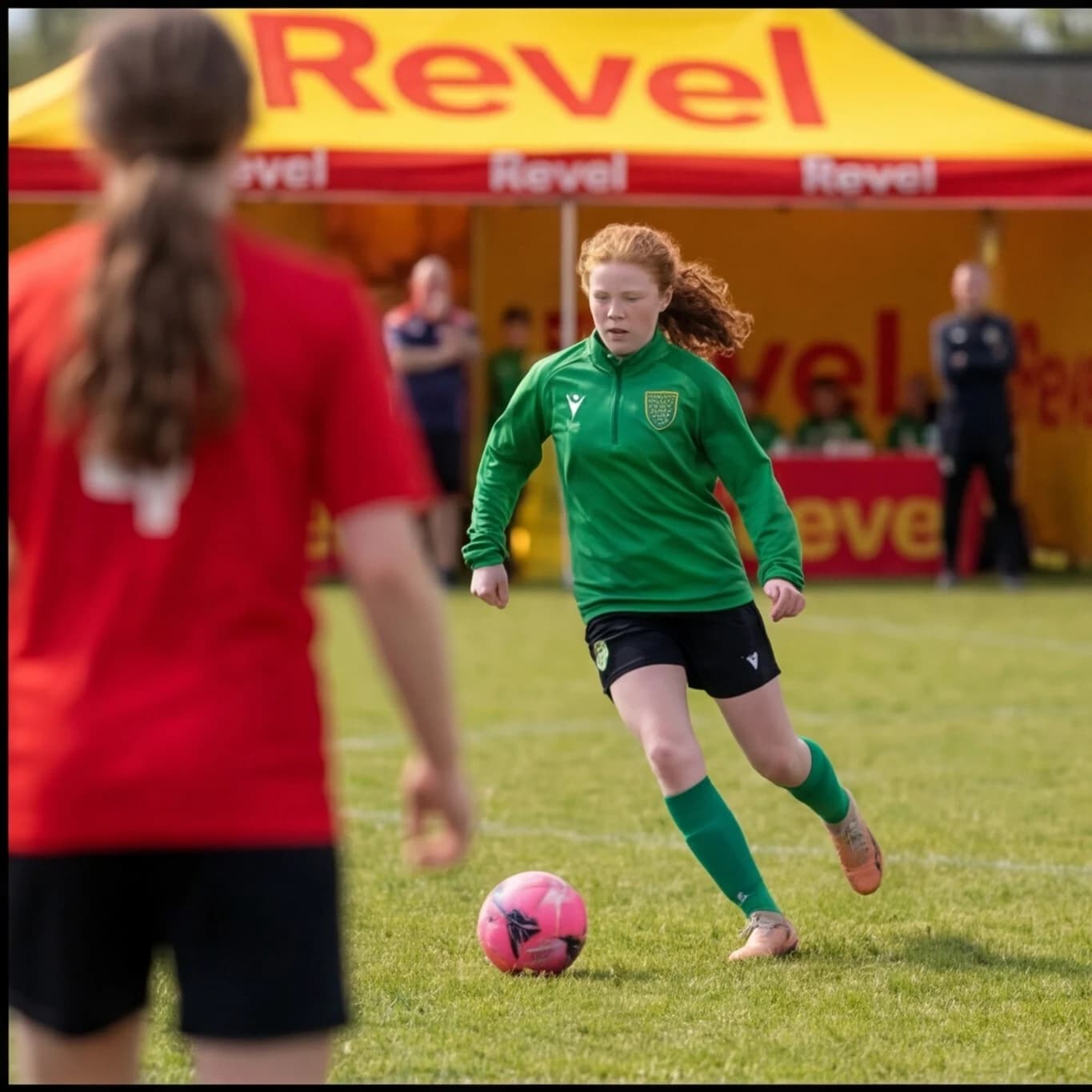 A girl in green running onto the ball in front of the Revel tent